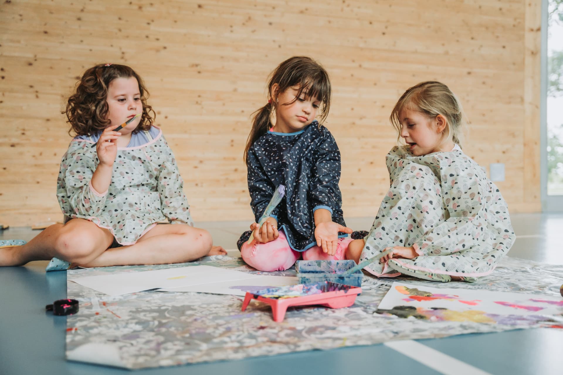 Kinder malen mit Pinsel und Farbe in der Turnhalle